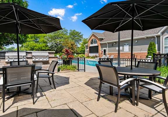 a patio with tables and umbrellas next to a swimming pool