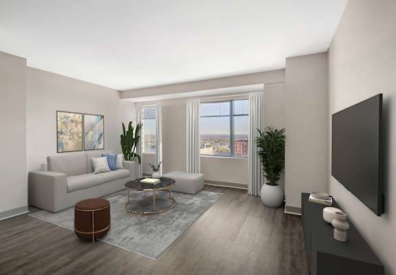 A living room with a grey couch, a coffee table, and a large window.