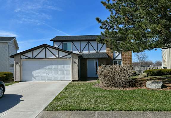 the front of a house with a white garage door and a lawn
