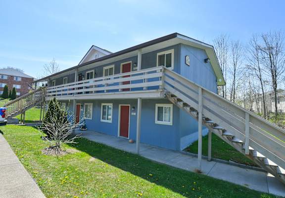 the front of a blue house with a deck and stairs