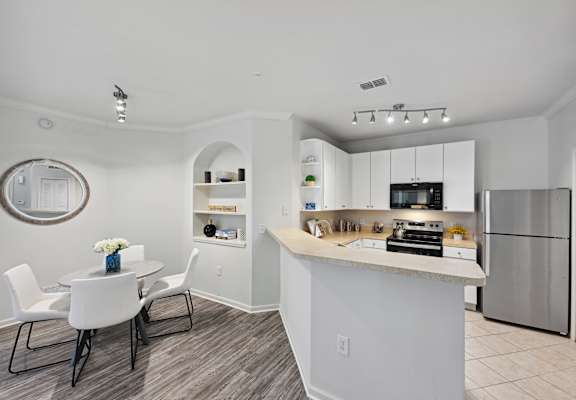 an open kitchen and dining area with a table and chairs and a refrigerator
