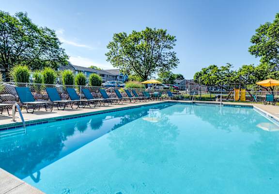A large swimming pool surrounded by lounge chairs and umbrellas.