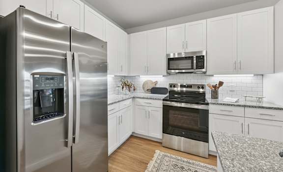 A modern kitchen with a stainless steel refrigerator and white cabinets.