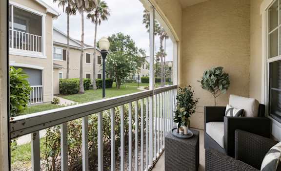 A balcony with a chair and a table with a plant on it.
