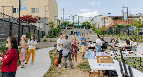 A group of people are gathered around tables outside a building.