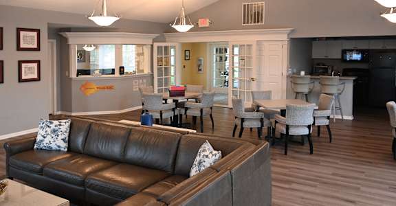 A living room with a brown leather couch and a wooden floor.