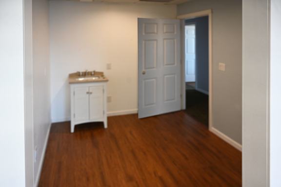 A white door is in a room with wood flooring.