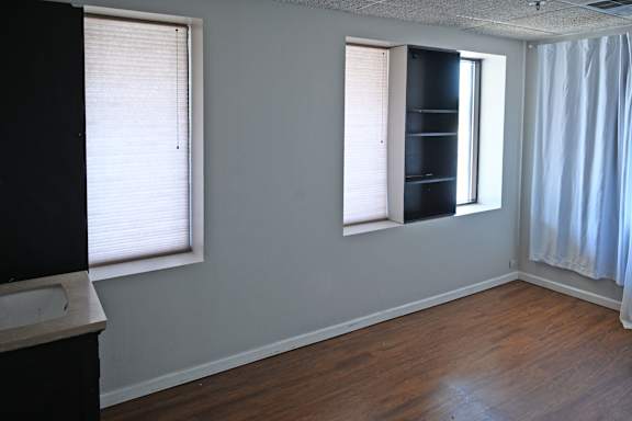 A room with a window and a wooden floor.
