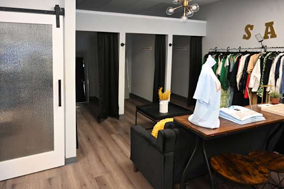 A room with a table, chairs, and a clothing rack.