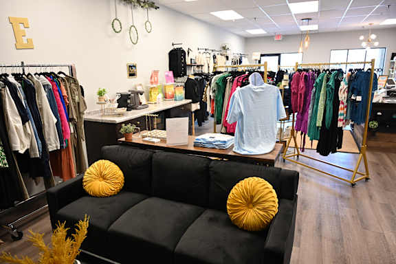 A man is standing in a clothing store looking at clothes.