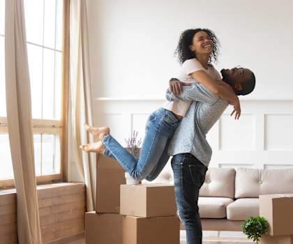 a woman holding a man in the air in a living room with boxes