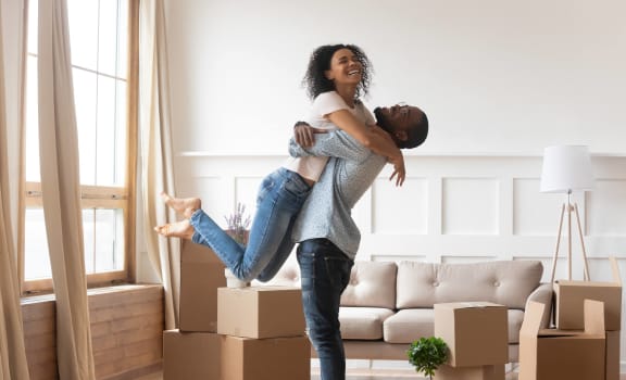 a woman holding a man in the air in a living room with boxes