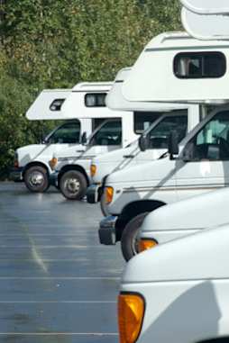A row of white RVs are parked in a lot.