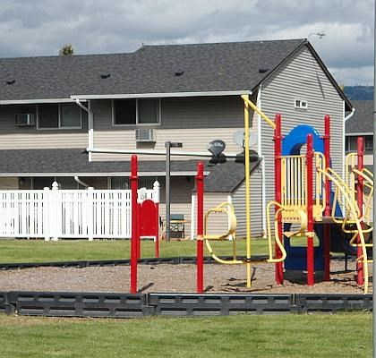 A playground with a swing set and a red slide.