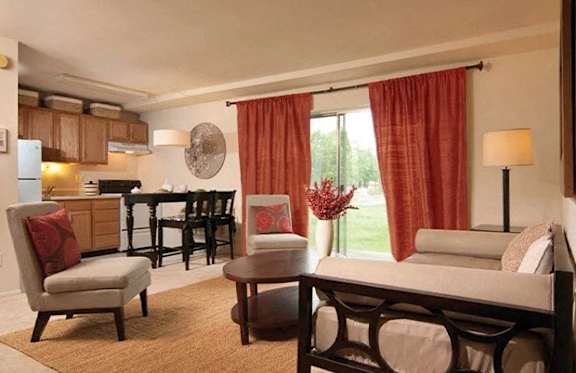 A well-lit bedroom with a bed, chair, and dining table.