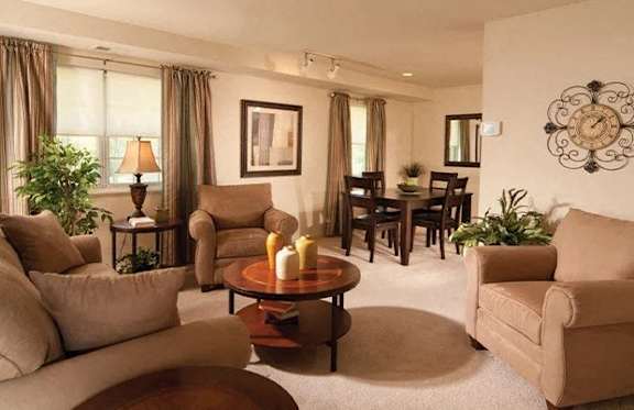 A living room with a brown sofa, a brown armchair, a brown coffee table, and a brown rug.