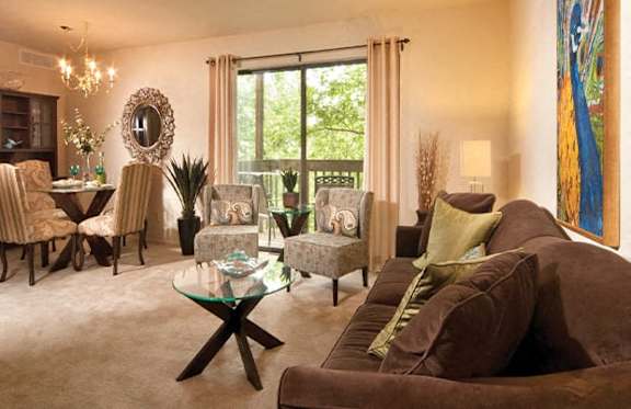A living room with a glass coffee table and brown couches.