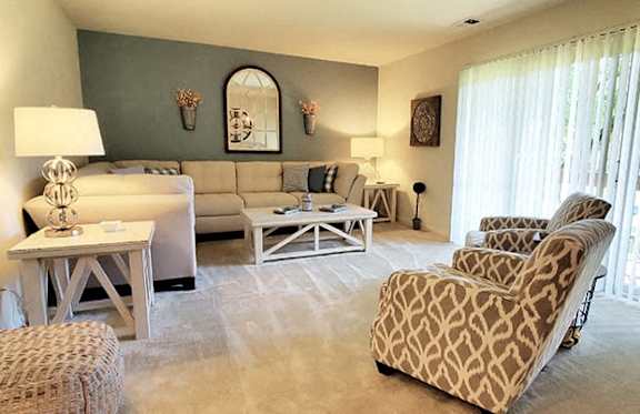 A living room with a white sofa, a patterned armchair, and a wooden coffee table.