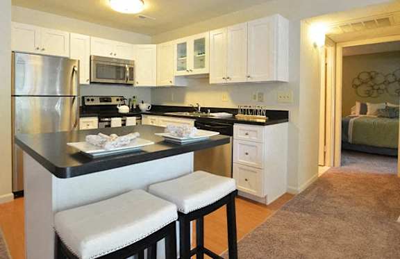 A kitchen with white cabinets and a black countertop.