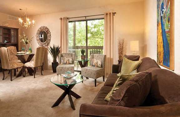 A living room with a glass coffee table and brown couches.