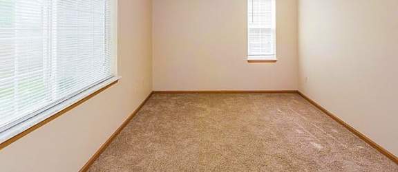an empty room with two windows and a carpeted floor