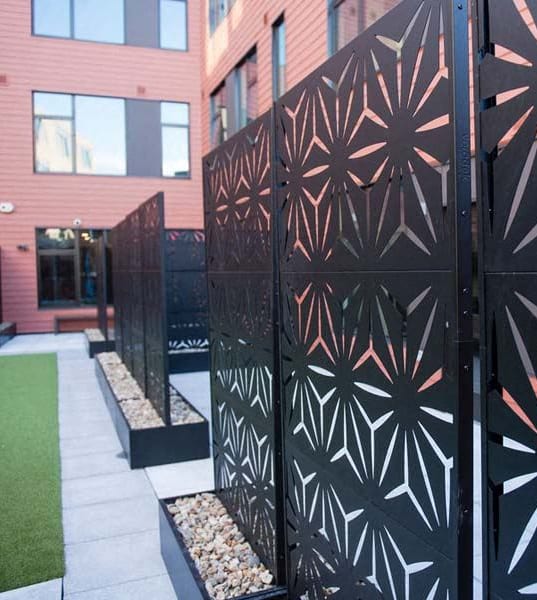 a black fence with geometric patterns in front of a building