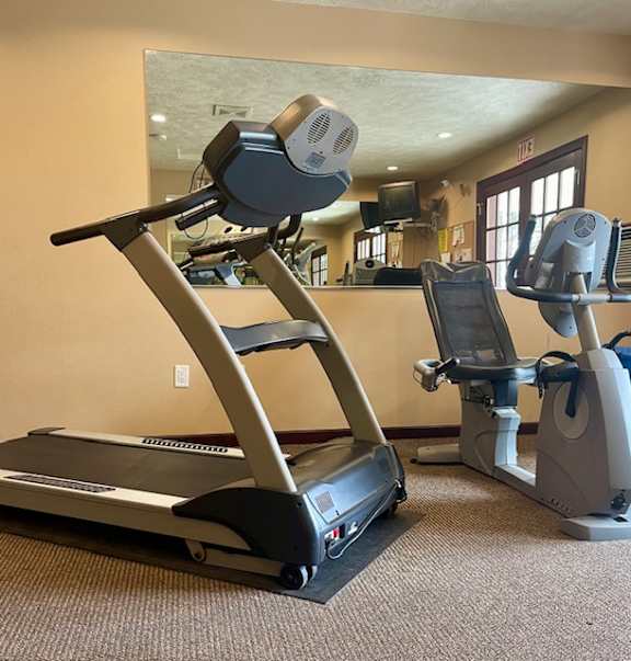 A treadmill and a stationary bike are in a gym.