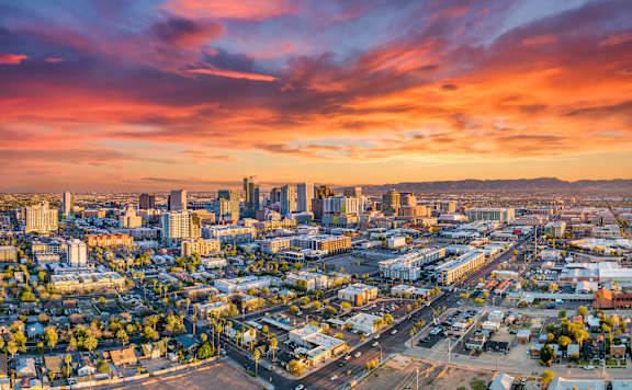 A cityscape with buildings and roads under a colorful sky.