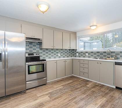 A kitchen with a refrigerator, oven, and microwave.
