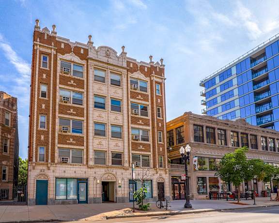 A large brown building with a blue door sits in front of a smaller building.