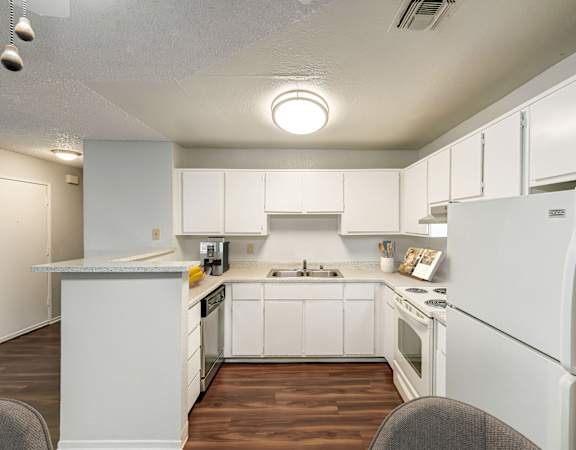 A white kitchen with a refrigerator, sink, and stove.