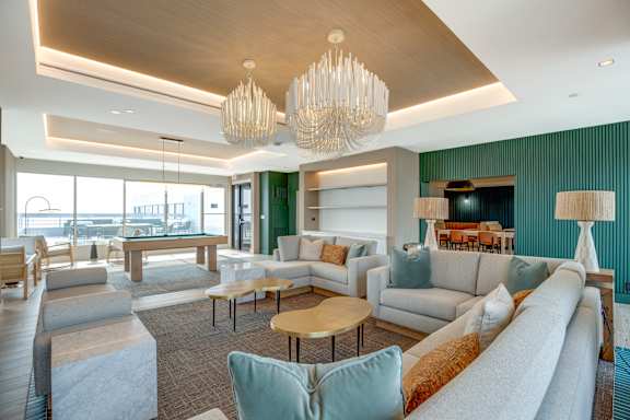 A large, modern living room with a long white sofa and a wooden coffee table.