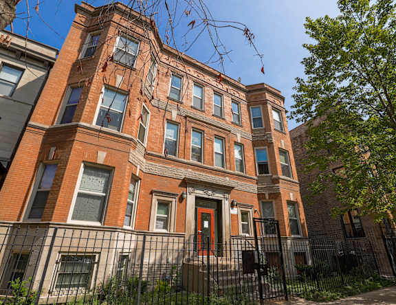 A red brick building with a black iron fence in front.