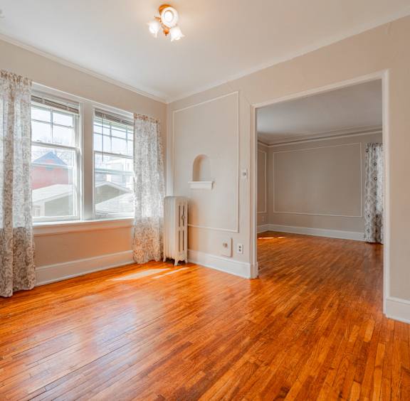 A room with wooden floors and a window with curtains.