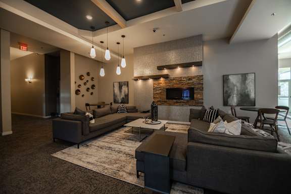 A modern living room with a stone fireplace and grey couches.