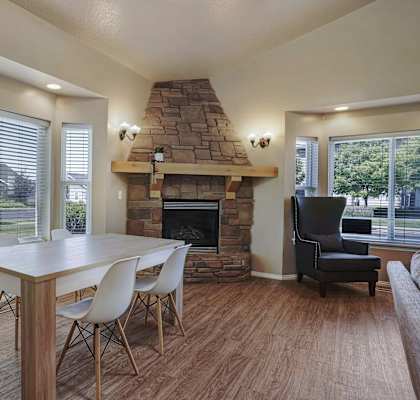 A dining room with a stone fireplace and a table with chairs.