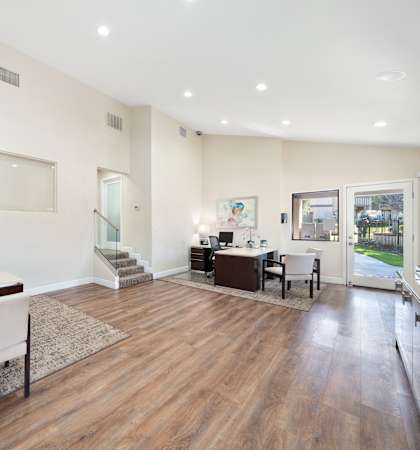 a living room with a desk and chairs and a glass door