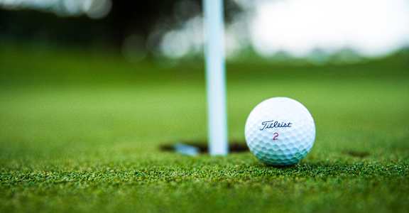 a golf ball sits next to a hole on the field