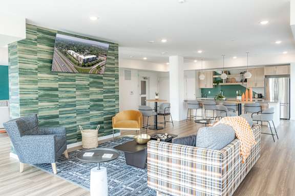 A living room with a plaid couch and a green wallpapered wall.