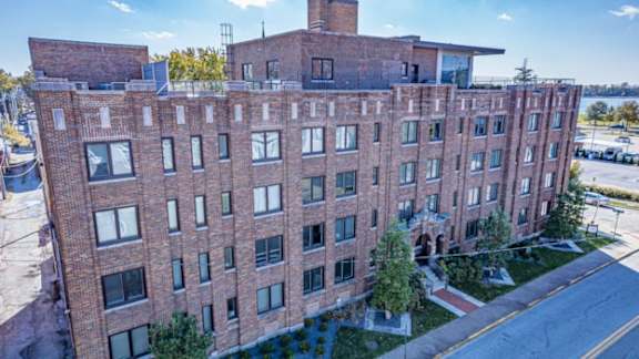 A large red brick building with a flat roof and a chimney on the top floor.