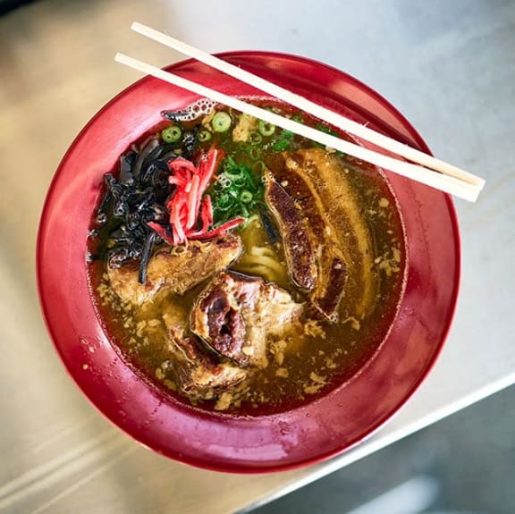 a bowl of soup with chopsticks on top of it