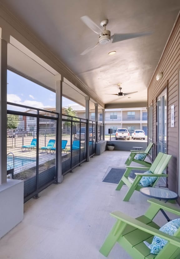 a porch with green chairs and a swimming pool