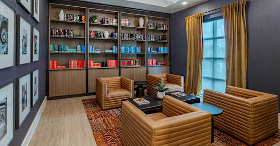 A room with a bookshelf, a table, and chairs.