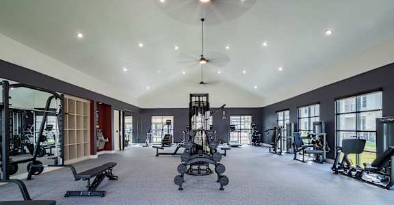 A spacious gym with a variety of equipment and a large mirror on the wall.
