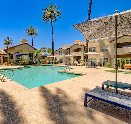A pool surrounded by palm trees and umbrellas.
