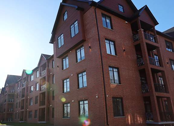 A large red brick building with multiple windows and balconies.
