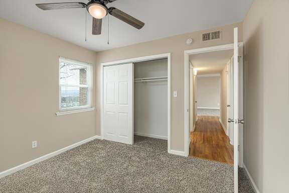 A room with a ceiling fan and carpeted floor.