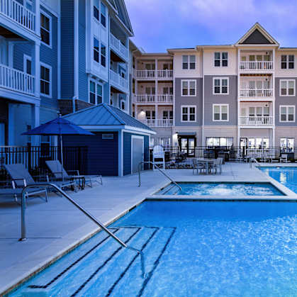 A swimming pool in front of a multi-story apartment building.