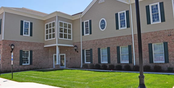 A building with a brick wall and a green lawn in front.