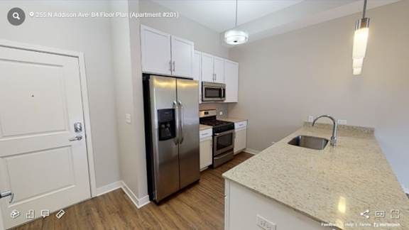 A kitchen with a refrigerator, oven, microwave, and sink.